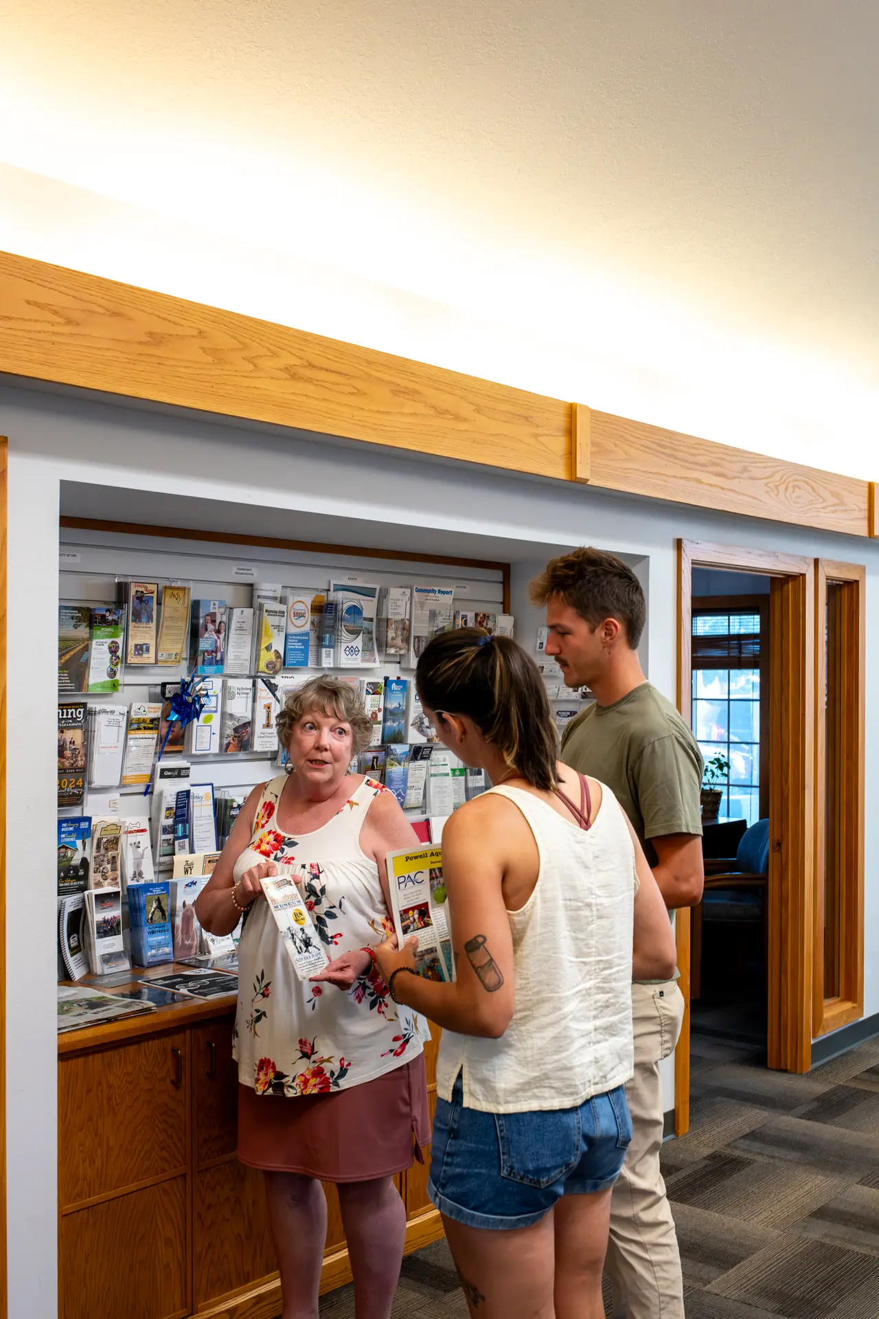 A staff member at the Powell Visitor Center assisting a young couple and handing them various flyers and posters