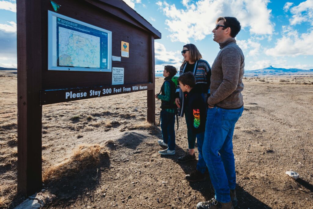A family of four reading the bulletin board with maps and posters at McCullough Peaks, near Powell, Wyoming