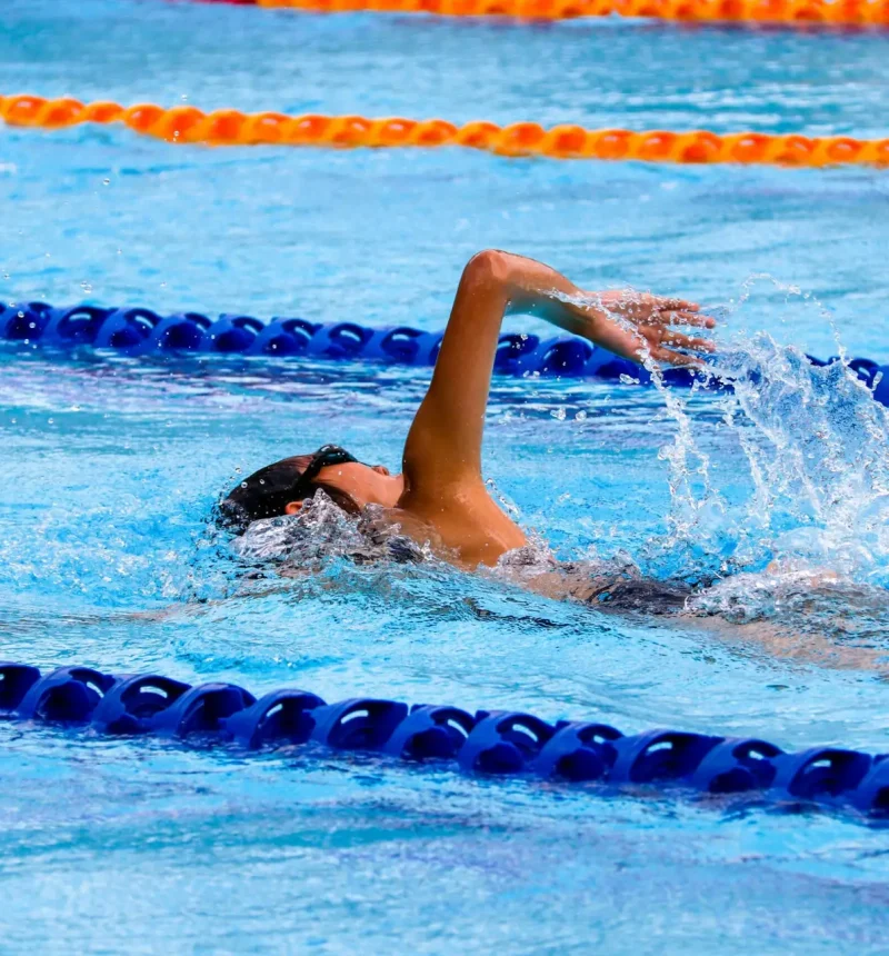 A girl swimming in an outdoor lap pool with lanes